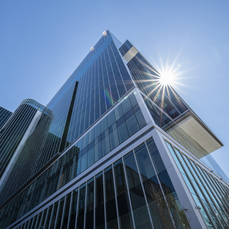 building exterior with glass windows and sun shining behind it