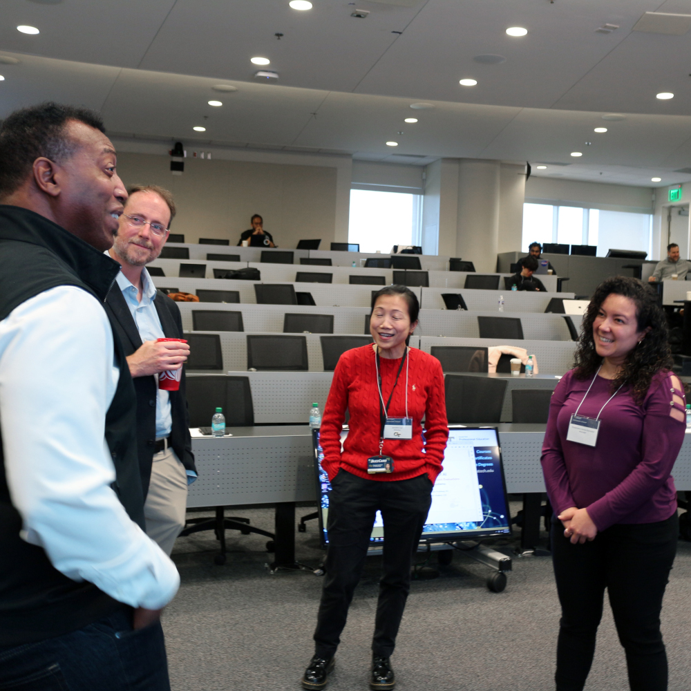 People standing and talking in front of a classroom