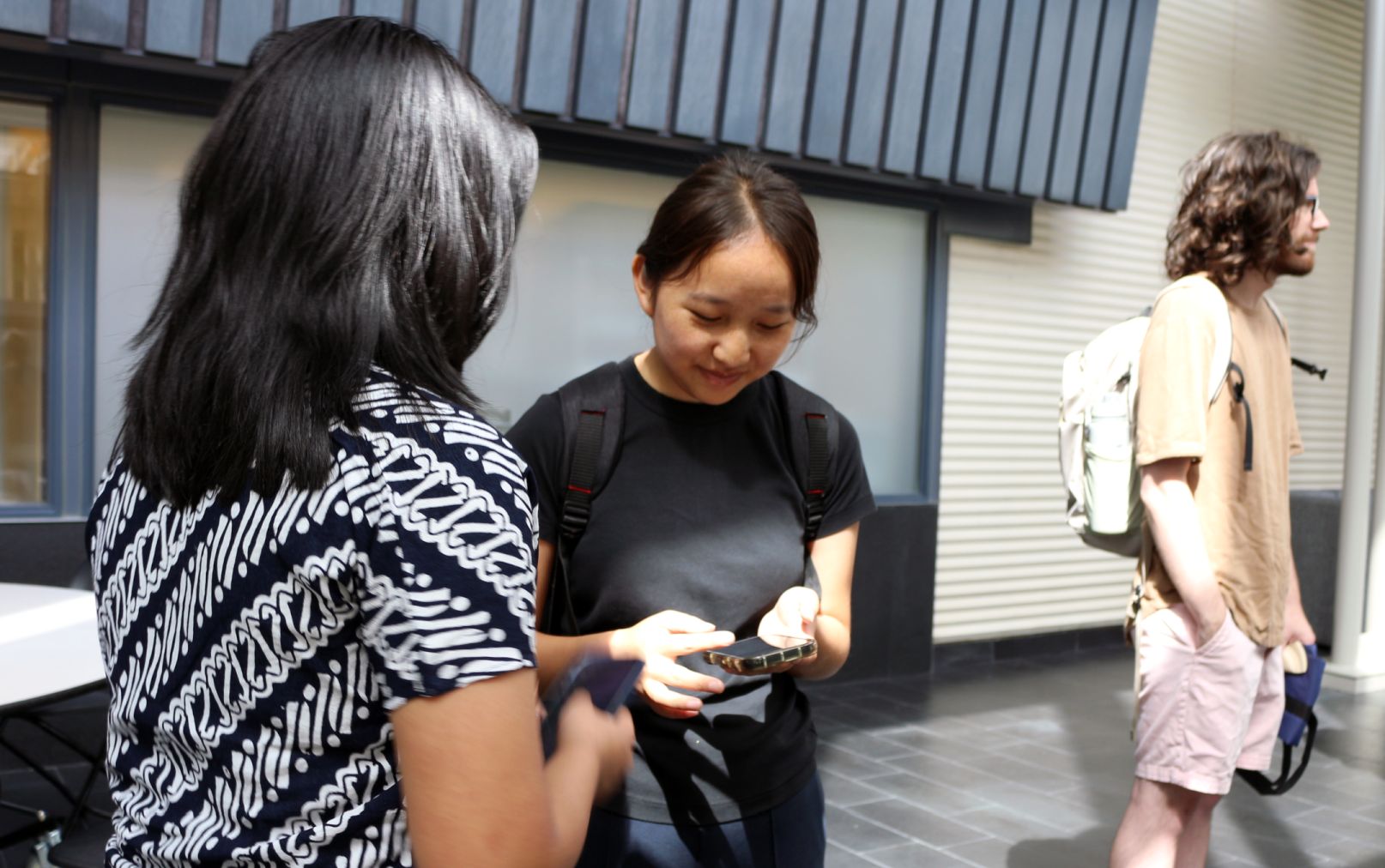 Two women exchange contact information at an academic poster session